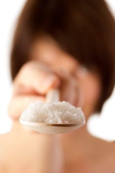Woman holding spoon with coarse salt
