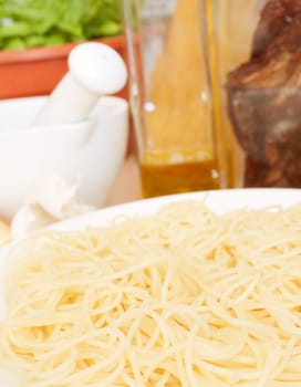 Italian Cuisine - spaghetti, dried tomatoes, garlic, basil, mortar with pestle and olive oil