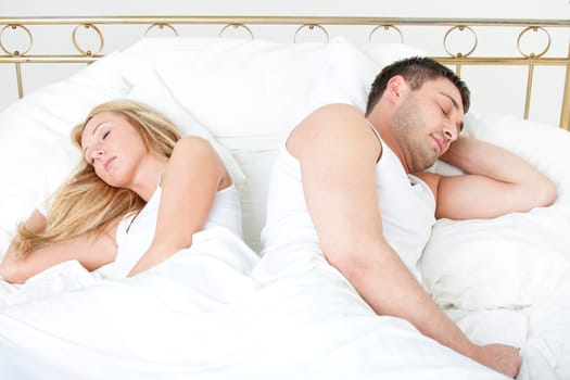 Couple sleeping back on back in bed