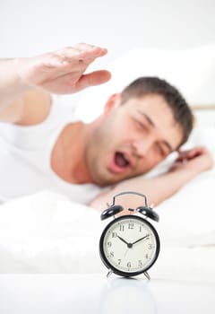 Sleeping man being awakened by an alarm clock