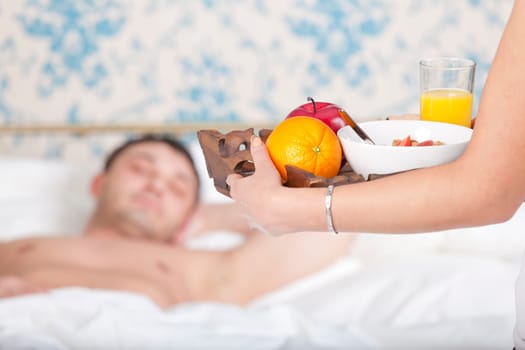 woman serving breakfast for man to bed at home