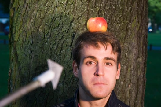 Head and shoulders shot of a young man at the tree with apple on his head and arrow at him from the camera