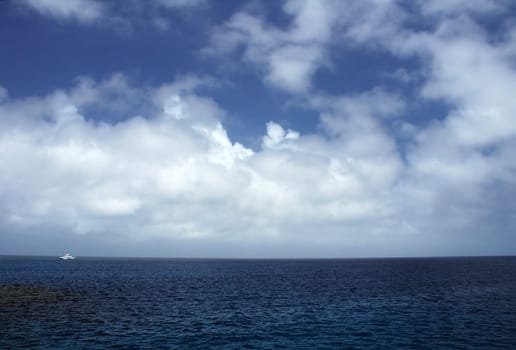 ocean scenery, blue sky with clouds, white boat in distance, location: Great Barrier Reef, near Cairns