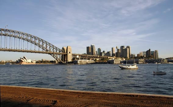 sydney view, opera house, harbour bridge and sydney tower visible, looks a little bit like rusty buildings because of the late afternoon light