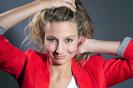 Young woman wearing a red top and holding her hair