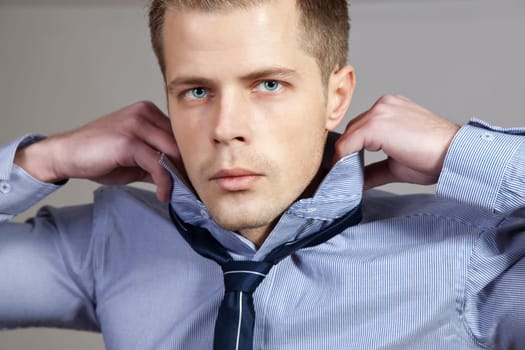 Portrait of a man adjusting his shirt and tie