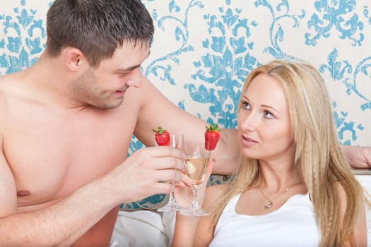 Young couple drinking sparkling wine in bed