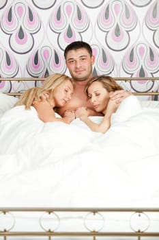 happy man lying with two women in bed