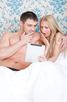 Couple in bed with tablet computer watching a movie