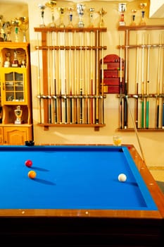 Billiard club with blue pool table cue in a row and winner trophy