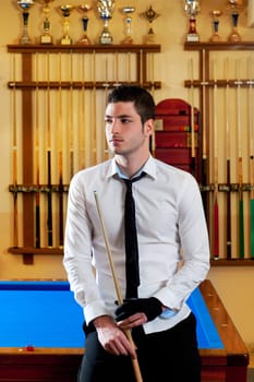 Billiard handsome young winner man with shirt tie and cue at trophy club