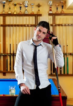 Billiard handsome young winner man with shirt tie and cue at trophy club