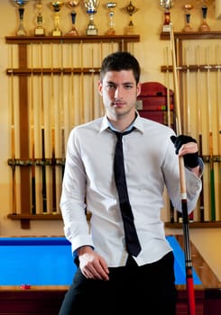 Billiard handsome young winner man with shirt tie and cue at trophy club