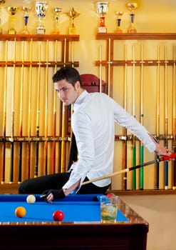 Billiard winner handsome man playing with cue and balls at club