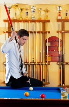 Billiard winner handsome man playing with cue and balls at club