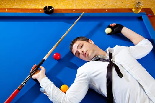 billiard young man player lying on pool blue table with balls