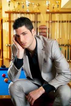 handsome man with suit sitting posing in billiard pool in club