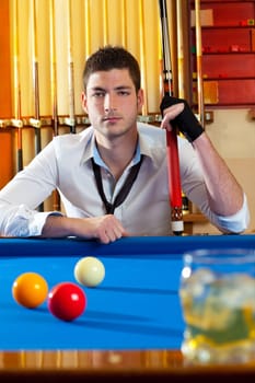 Billiard expertise man posing on blue with alcohol on the rocks glass