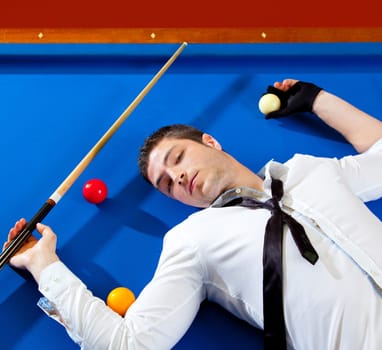 billiard young man player lying on pool blue table with balls