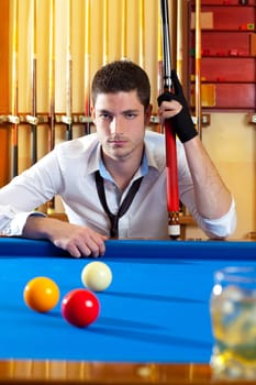 Billiard expertise man posing on blue with alcohol on the rocks glass