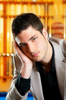 handsome man with suit sitting posing in billiard pool in club