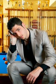 handsome man with suit sitting posing in billiard pool in club