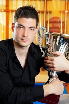 Happy proud winner man with big trophy silver cup in billiard club