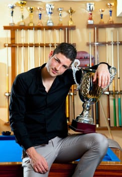Happy proud winner man with big trophy silver cup in billiard club
