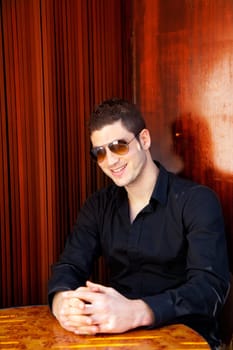 Latin mediterranean handsome man in wooden corner with sunglasses
