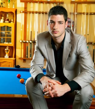 handsome man with suit sitting posing in billiard pool in club