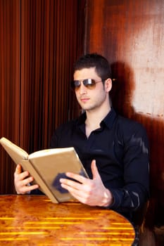 Latin tourist man reading a map book with sunglasses