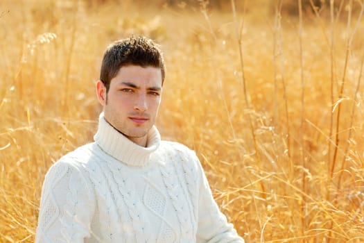 Autumn winter man portrait in outdoor dried grass field with turtleneck sweater