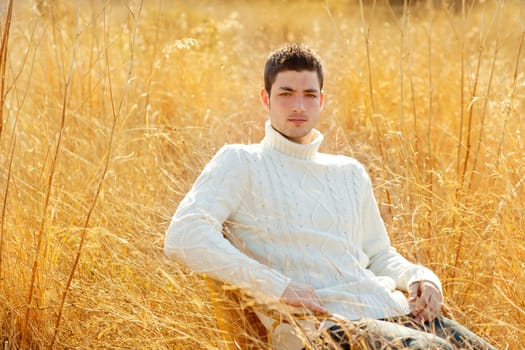 Autumn winter man portrait in outdoor dried grass field with turtleneck sweater