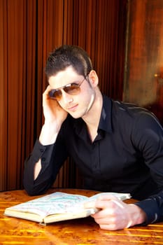 Latin tourist man reading a map book with sunglasses