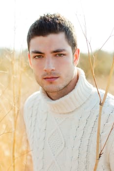 Autumn winter man portrait in outdoor dried grass field with turtleneck sweater
