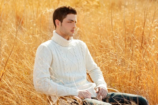 Autumn winter man portrait in outdoor dried grass field with turtleneck sweater