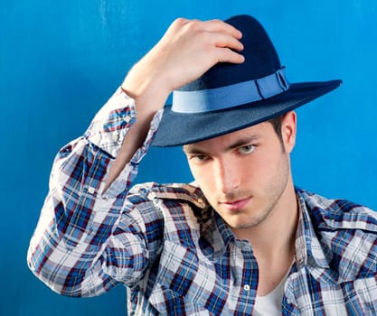 handsome young man with plaid shirt and cowboy hat on blue background