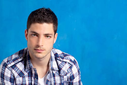 handsome young man with plaid shirt on blue background