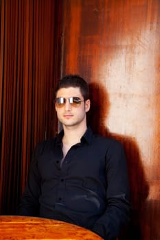 Latin mediterranean handsome man in wooden corner with sunglasses