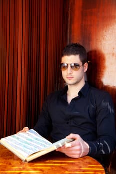 Latin tourist man reading a map book with sunglasses