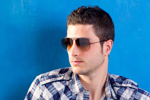 handsome young man with plaid shirt and sunglasses on blue background