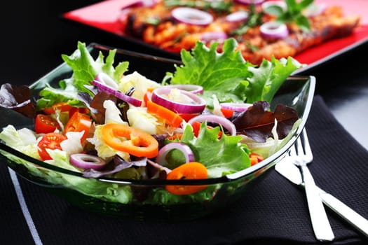 Mixed vegetable salad grilled meat in background