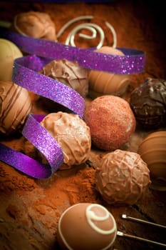 Pralines with vignette and a purple ribbon on a cocoa powdered background