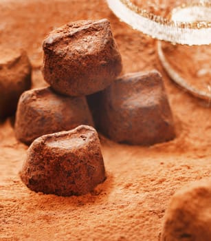 Handmade luxury chocolate bonbons sprinkled with, and lying in, cocoa powder with gold festive ribbon
