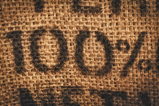 Background of woven textured hessian stamped with one hundred percent - 100 percent - in numerals