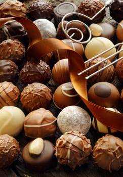 Background of an assortment of different decorative luxury chocolates with an ornamental ribbon