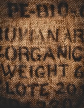 Vertical background of a twenty kilogram hessian coffee bag stamped and certified one hundred percent organic