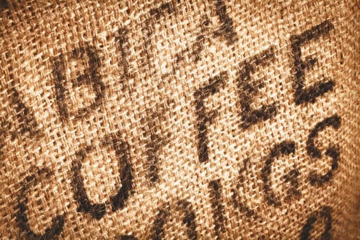 Close up of textured woven hessian fabric with the word Coffee stamped on it in a coffee background concept