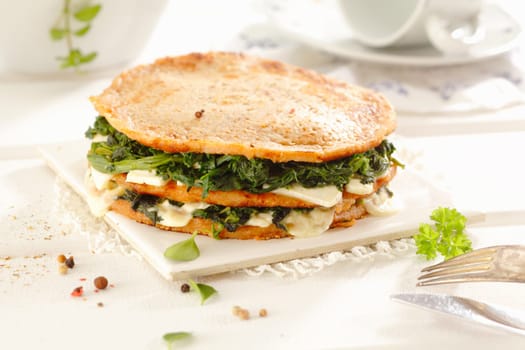 Delicios snack or light luncheon of three wholewheat pancakes stacked with a filling of cheese, spinach and greens.
