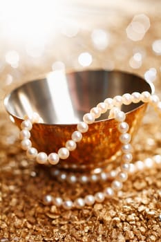 Necklace of matched pearls and a silver bowl with a festive sparkling bokeh of party lights